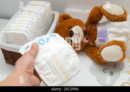 Pcture of a brown teddy bear with diaper on sitting in baby bed Stock Photo