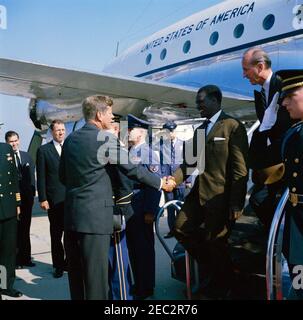 Arrival ceremony for Ahmed Su00e9kou Touru00e9, President of Guinea, 11:00AM. President John F. Kennedy shakes hands with President of Guinea, Ahmed Su00e9kou Touru00e9, upon President Touru00e9u0027s arrival at Washington National Airport. U.S. Chief of Protocol, Angier Biddle Duke, descends airplane stairs behind President Touru00e9; U.S. Assistant Chief of Protocol for Visits and Public Events, Samuel L. King (over President Kennedyu0027s shoulder), stands at left in background. Military Air Transport Service (MATS) terminal, Washington National Airport, Washington D.C.