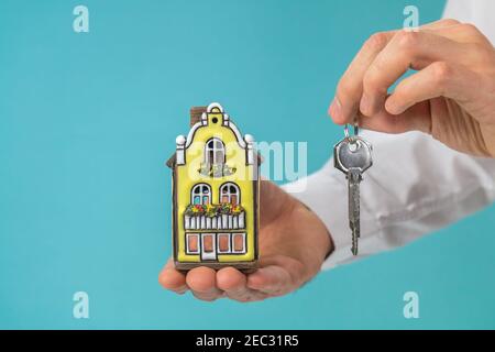 Nice house model and key in hand, turquoise background for copy space - real estate concept Stock Photo