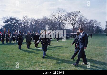 Arrival ceremonies for Abdirashid Ali Shermarke, Prime Minister of the Somali Republic, 11:45AM. President John F. Kennedy walks with Prime Minister of the Somali Republic, Dr. Abdirashid Ali Shermarke, during arrival ceremonies in honor of Prime Minister Shermarke; an unidentified Commander of Troops walks left of President Kennedy and the Prime Minister. Military color and honor guard troops stand at attention in background. South Lawn, White House, Washington, D.C. [Blemishes on image are original to the negative.] Stock Photo