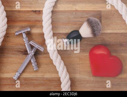 Two razors, brush, heart and rope on a wooden background Stock Photo