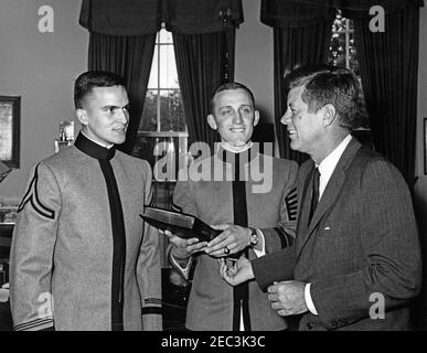 Presentation of the US Military Academy at West Point Yearbook, Howitzer, to President Kennedy, 12:12PM. United States Military Academy cadets of West Point present President John F. Kennedy with a copy of the 1963 u0022Howitzeru0022 yearbook. (L-R) Cadet David W. Knowlton, editor of the yearbook; Cadet First Captain Lyndol L. Cook, class president; and President Kennedy. Oval Office, White House, Washington, D.C. Stock Photo