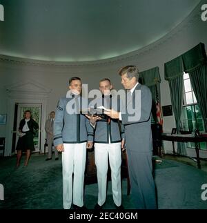 Presentation of the US Military Academy at West Point Yearbook, Howitzer, to President Kennedy, 12:12PM. United States Military Academy cadets of West Point present President John F. Kennedy with a copy of the 1963 u0022Howitzeru0022 yearbook. Left to right, in foreground: Cadet David W. Knowlton, editor of the yearbook; Cadet First Captain Lyndol L. Cook, class president; and President Kennedy. An unidentified woman (left) and White House Secret Service agent Frank Yeager stand in the background. Oval Office, White House, Washington, D.C. Stock Photo