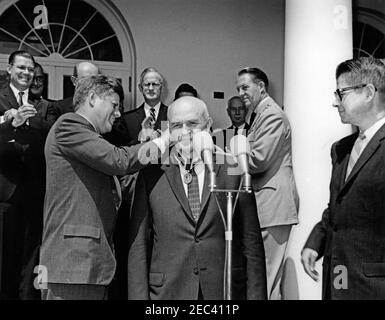 Presentation of the Distinguished Civilian Service Awards, 11:30AM. President John F. Kennedy presents the Presidentu0027s Award for Distinguished Federal Civilian Service to Associate Administrator of the Economic Research Service of the Department of Agriculture, Dr. Sherman E. Johnson (center, behind microphones), at a ceremony in the Rose Garden of the White House, Washington, D.C. Secretary of Agriculture, Orville Freeman, observes at right. Standing in the background (left to right): Secretary of Defense, Robert S. McNamara; Vice President Lyndon B. Johnson (in back); Secretary of State Stock Photo