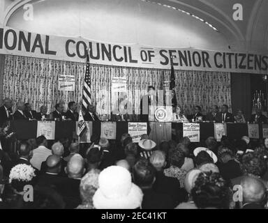 Address to the National Convention of the National Council of Senior Citizens, 11:47AM. President John F. Kennedy (at lectern) delivers an address to attendees of the National Convention of the National Council of Senior Citizens at the Willard Hotel, Washington D.C. On stage (L-R): Council Vice President, Burt Garnett; three unidentified; Secretary of the Department of Health, Education, and Welfare, Anthony J. Celebrezze; Senator Birch Evans Bayh, Jr. of Indiana; Director of Special Projects for the Council, Lawrence A. Oxley; Council Chairman, John Fitzpatrick; President Kennedy; two uniden Stock Photo