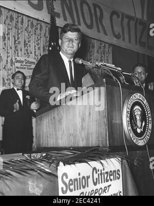 Address to the National Convention of the National Council of Senior Citizens, 11:47AM. President John F. Kennedy (at lectern) delivers an address to attendees of the National Convention of the National Council of Senior Citizens at the Willard Hotel, Washington D.C. Executive Director of the Council, Dr. Blue Carstenson, applauds behind President Kennedy. Stock Photo