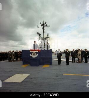 Trip to Western States: Visit to the Pacific Fleet, President Kennedy aboard the USS Oriskany, 4:00PM. President John F. Kennedy (center left) and Commander-in-Chief of the Pacific Fleet (CINCPACFLT), Admiral John H. Sides (right, saluting), stand on the reviewing platform aboard the flight deck of the aircraft carrier USS Oriskany (CVA-34) as ships from the task force perform a 21-gun salute in honor of President Kennedyu0027s visit to the U.S. Pacific Fleet, at sea off the coast of San Diego, California. Standing right of platform (left to right): Commander of Carrier Division One, Rear Adm Stock Photo