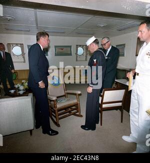 Trip to Western States: Visit to the Pacific Fleet, President Kennedy aboard the USS Kitty Hawk, 5:00PM. President John F. Kennedy receives a rocking chair in honor of his visit to the U.S. Pacific Fleet aboard the USS Kitty Hawk (CVA-63), at sea off the coast of San Diego, California; the back and seat covers on the chair were embroidered by Boatswainu0027s Mate, Second Class, Jesse R. u0022J. R.u0022 Johnson (third from right). Left to right: Special Assistant to the President, Kenneth P. Ou0027Donnell (in back); President Kennedy; Boatswainu0027s Mate Johnson; Secretary of the Navy Fre Stock Photo