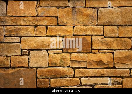 A yellow orange sandstone wall with square rectangle shaped bricks Stock Photo
