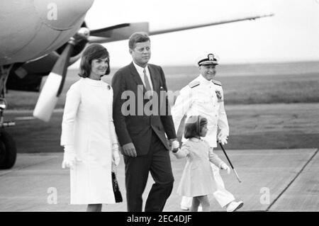 Arrival of First Lady Jacqueline Kennedy (JBK) u0026 Caroline Kennedy (CBK) from Italy. President John F. Kennedy greets First Lady Jacqueline Kennedy and Caroline Kennedy (holding her fatheru0027s hand) upon their arrival at Quonset Point Naval Air Station from Italy. An unidentified US Navy officer walks at right; the airplane u0022Carolineu0022 is visible at left in background. North Kingstown, Rhode Island. Stock Photo