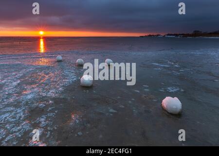 Beautiful sunset over the Bay of Gdansk in Jastarnia. Natural snow balls on the beach. Winter landscape. Poland. Stock Photo
