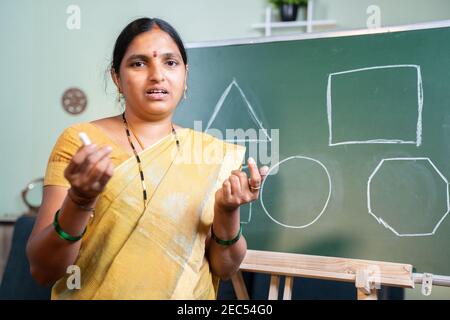 Indian woman busy explaining during online class by looking camera at home - Concept of e-teaching, Remote learning, virtual education during Stock Photo