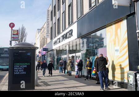 Brighton UK 13th February 2021 - Shoppers queue to get in the Marks & Spencer store in Western Road Brighton as the governments coronavirus COVID-19 lockdown restrictions continue . The shoppers were believed to be hoping to buy the M&S Valentine meal deal offer ready for Valentines Day tomorrow: Credit Simon Dack / Alamy Live News Stock Photo