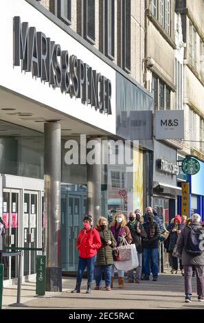 Brighton UK 13th February 2021 - Shoppers queue to get in the Marks & Spencer store in Western Road Brighton as the governments coronavirus COVID-19 lockdown restrictions continue . The shoppers were believed to be hoping to buy the M&S Valentine meal deal offer ready for Valentines Day tomorrow: Credit Simon Dack / Alamy Live News Stock Photo
