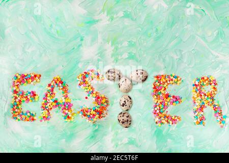 Easter text on a green background with brush strokes with quail eggs letter T. Spring card. Copy space Stock Photo