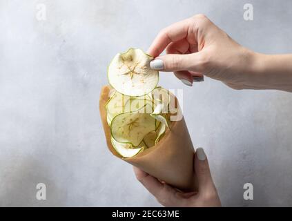 female hands holding paper package with dried apple chips Stock Photo