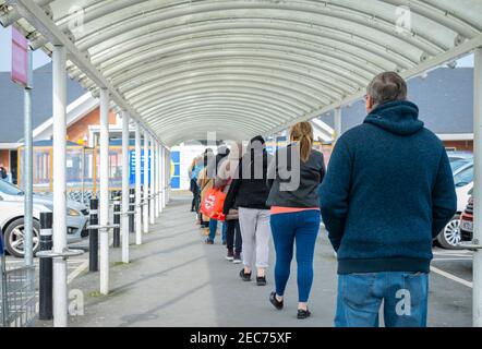 Long queue of people how waiting to entry into the Tesco store. Tesco store Redditch, United Kingdom, 13 Feb 2021 Stock Photo