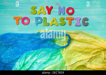 Plastic bags and inscription of colorful wooden letters: say no to plastic. Flat lay, wooden turquoise background. Ban plastic concept Stock Photo