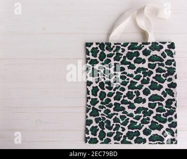 Eco Shopping Bag in trendy leopard pattern print on white wooden background, Top View, Flat Lay, mock-up Stock Photo