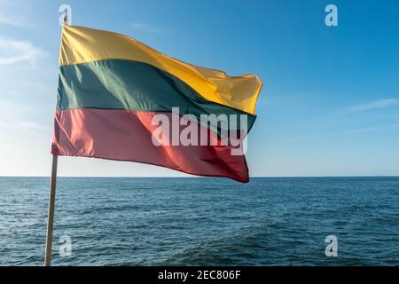 Flag of Lithuania on blue sky background flying in strong breeze over the Baltic sea. Lithuanian national flag. Stock Photo