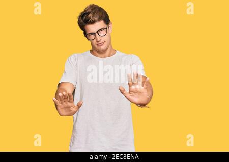 Handsome caucasian man wearing casual clothes and glasses moving away hands palms showing refusal and denial with afraid and disgusting expression. st Stock Photo