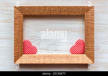 Wooden frame for photo, picture or text and pair of handmade Valentine's day love red checkered hearts in it on aged textured wooden white painted wal Stock Photo