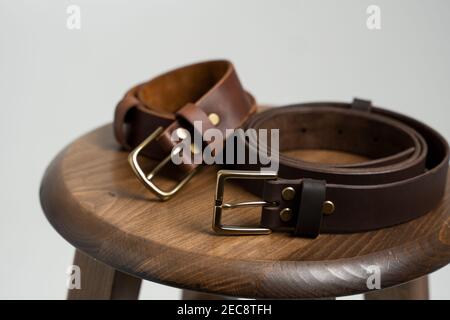 Two brown leather men's belts with bronze clasp on wooden chair with a  white background. Handmade leather belt Stock Photo - Alamy