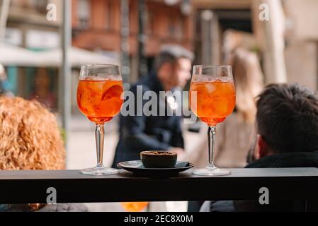 couple of two italian drink aperol spritz glasses on bar top with traditional italian happy hour aperitivo with olives. outdoor people in bar terrace Stock Photo