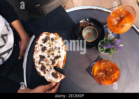 young woman eating italian bruschetta with mozzarella cheese doing italian happy hour with spritz drink known as aperitivo and starters in bar terrace Stock Photo