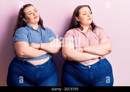 Young plus size twins wearing casual clothes looking to the side with arms crossed convinced and confident Stock Photo