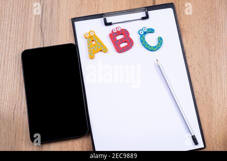 Online learning, back to university, new content project, remote education . Digital tablet computer with black mockup. Alphabet on white sheet folder Stock Photo