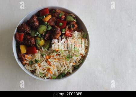Vegetable Carrot Fried Rice with Indian spices served along with chilly chicken. Homemade food shot on white background Stock Photo