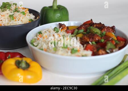 Vegetable Carrot Fried Rice with Indian spices served along with chilly chicken. Homemade food shot on white background Stock Photo