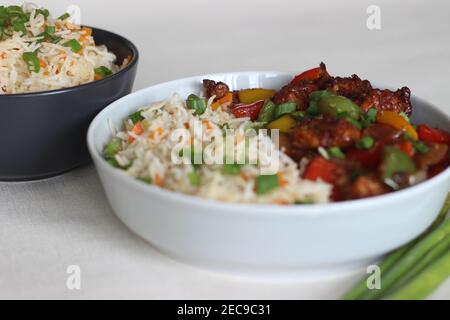 Vegetable Carrot Fried Rice with Indian spices served along with chilly chicken. Homemade food shot on white background Stock Photo