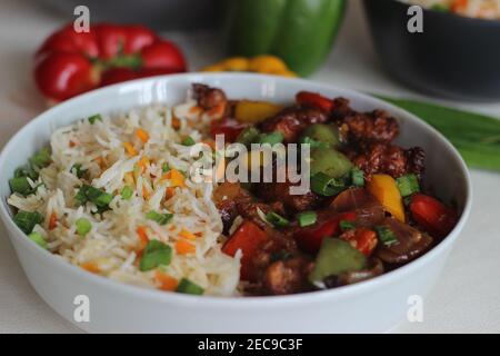 Vegetable Carrot Fried Rice with Indian spices served along with chilly chicken. Homemade food shot on white background Stock Photo