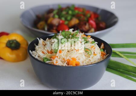 Vegetable Carrot Fried Rice with Indian spices served along with chilly chicken. Homemade food shot on white background Stock Photo