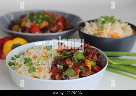 Vegetable Carrot Fried Rice with Indian spices served along with chilly chicken. Homemade food shot on white background Stock Photo