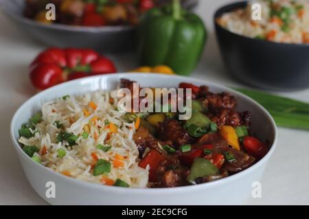 Vegetable Carrot Fried Rice with Indian spices served along with chilly chicken. Homemade food shot on white background Stock Photo