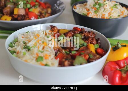 Vegetable Carrot Fried Rice with Indian spices served along with chilly chicken. Homemade food shot on white background Stock Photo