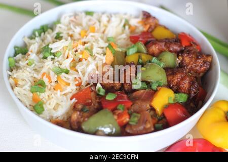 Vegetable Carrot Fried Rice with Indian spices served along with chilly chicken. Homemade food shot on white background Stock Photo