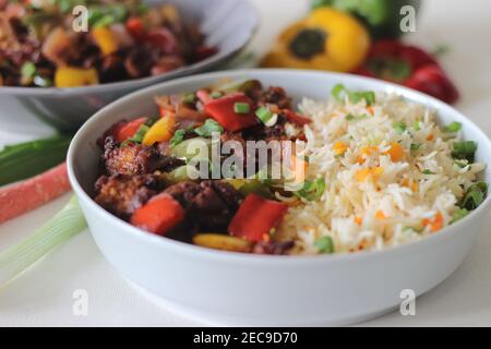Vegetable Carrot Fried Rice with Indian spices served along with chilly chicken. Homemade food shot on white background Stock Photo