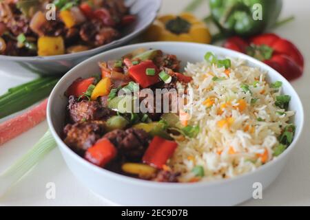Vegetable Carrot Fried Rice with Indian spices served along with chilly chicken. Homemade food shot on white background Stock Photo