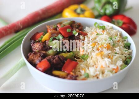 Vegetable Carrot Fried Rice with Indian spices served along with chilly chicken. Homemade food shot on white background Stock Photo