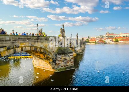 Late afternoon in Prague Czechia as tourists walk across the Charles Bridge of the River Vltava with St Vitus Cathedral and Prague Castle in view. Stock Photo