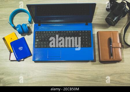 top view office desk. laptop and blue headphones, notepad, photo reflex camera, passports and vaccination letter to travel on wooden table. concept wo Stock Photo