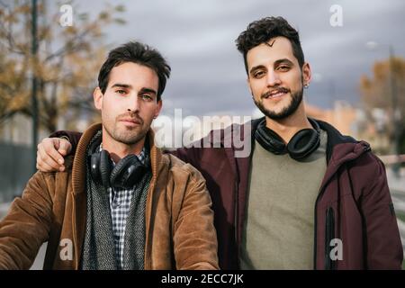 Couple of gay guys looking at camera while hugging each other. Stock Photo