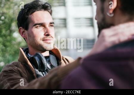 Handsome gay man looks at his boyfriend lovingly as he caresses his face Stock Photo