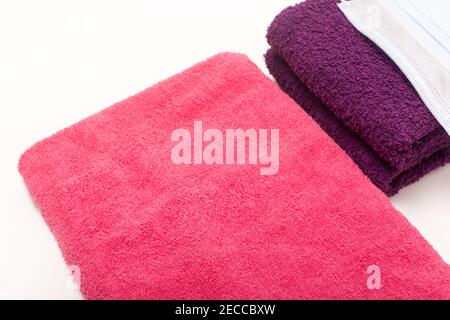 Rose and violet towels on white background, hygiene masks on bath towels Stock Photo