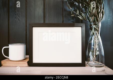 Empty wooden frame, metal coffee cup, book and olive branch Stock Photo