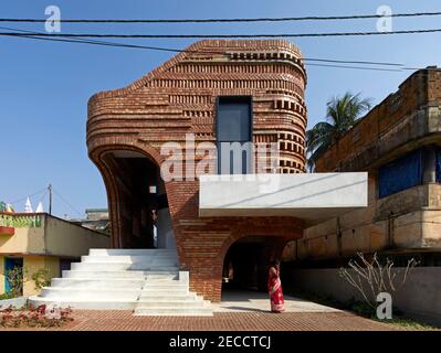 Exterior facade view in late afternoon with woman on phone. The Gallery House, Bansberia, India. Architect: Abin Design Studio, 2020. Stock Photo